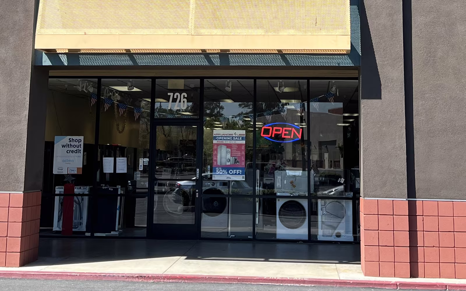The Appliances 4 Less entrance at 726 N Main St in Corona, with the OPEN sign and appliances in the windows
