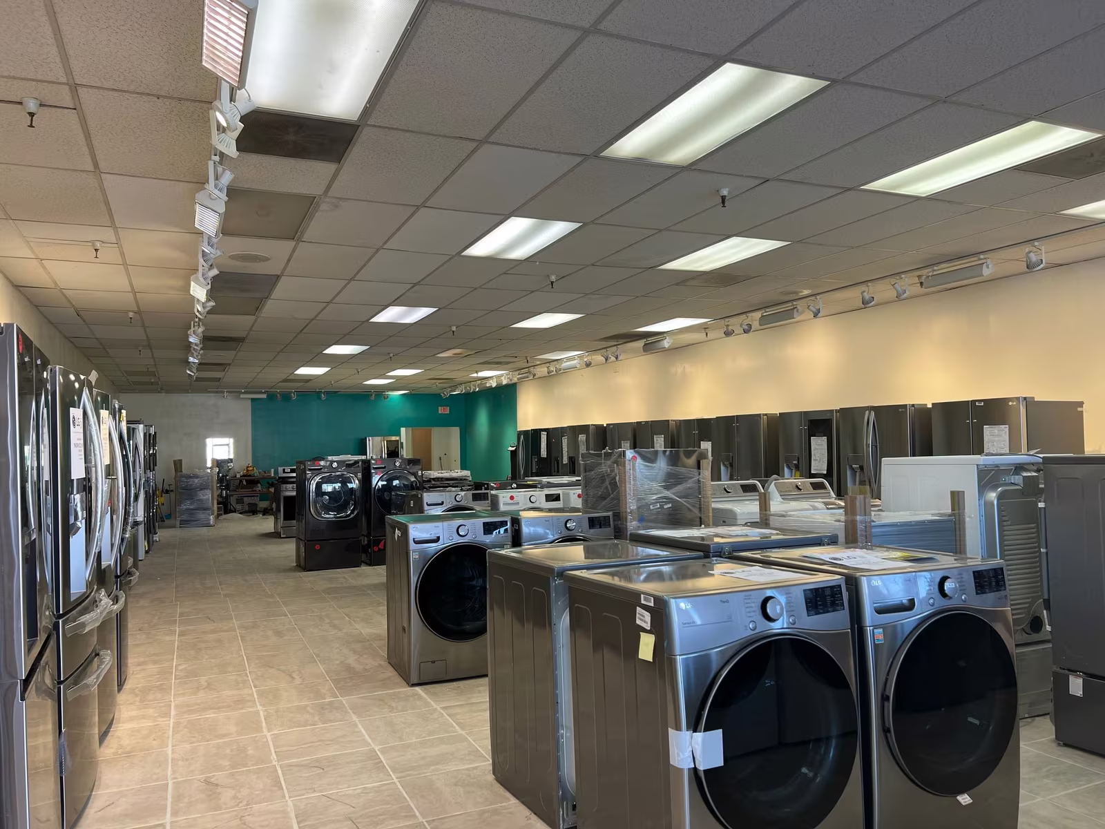 Refrigerators and front-load washers down the length of the Appliances 4 Less Corona showroom